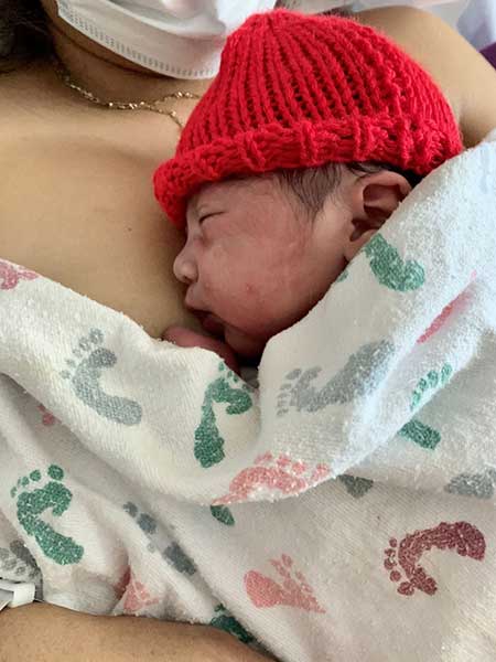 Mother Embracing Newborn Child With a Red Hat