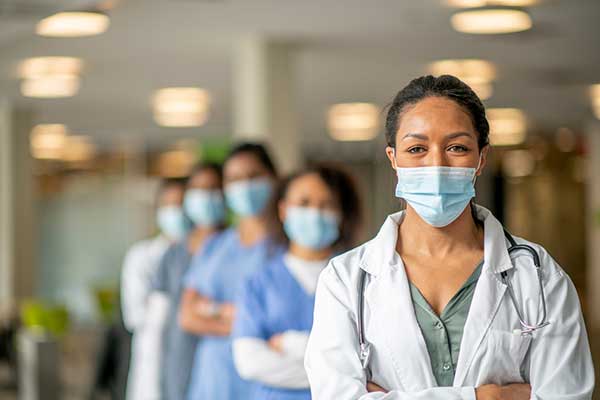 Female doctor and nurses in mask lined up behind one another
